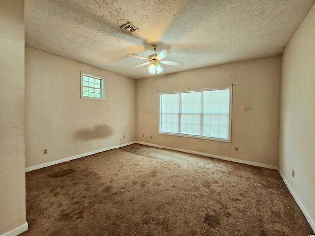 empty room featuring ceiling fan, a textured ceiling, carpet, and baseboards