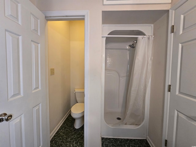 bathroom with baseboards, a shower stall, and toilet