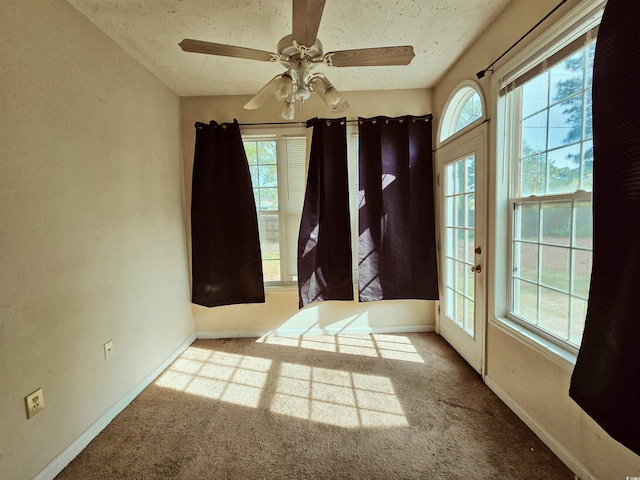 unfurnished room featuring carpet flooring, ceiling fan, baseboards, and a textured ceiling