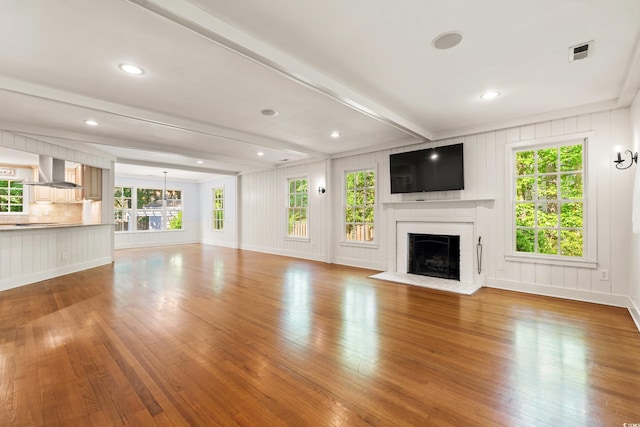 54 River Birch Ln, Pawleys Island, SC 29585 - unfurnished living room featuring wood finished floors, a fireplace, beam ceiling, baseboards, and a decorative wall