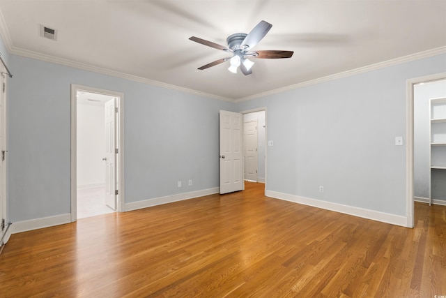 54 River Birch Ln, Pawleys Island, SC 29585 - unfurnished bedroom featuring a walk in closet, ornamental molding, light wood-type flooring, baseboards, and ensuite bath