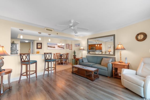 living area featuring crown molding, wood finished floors, and a ceiling fan