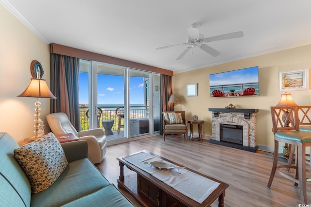 living area with crown molding, wood finished floors, a fireplace, and a ceiling fan