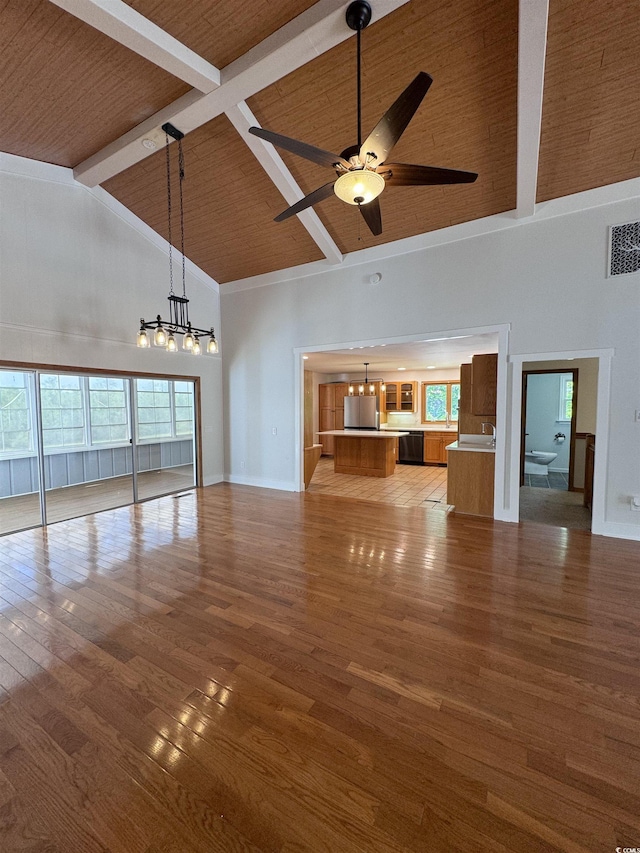 unfurnished living room with high vaulted ceiling, a chandelier, wood finished floors, beam ceiling, and a ceiling fan