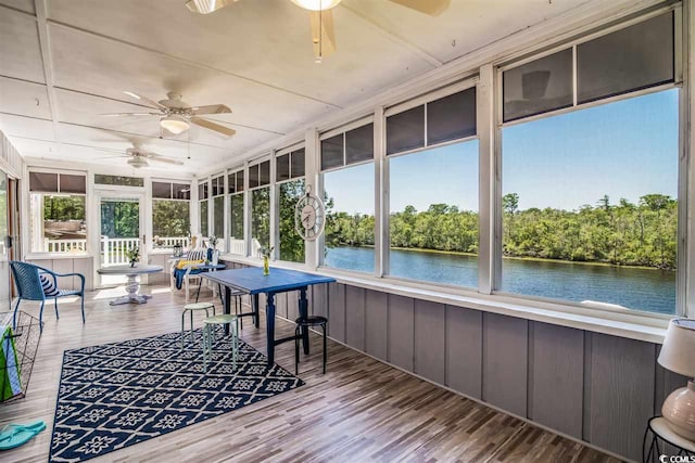 sunroom / solarium with ceiling fan and a water view