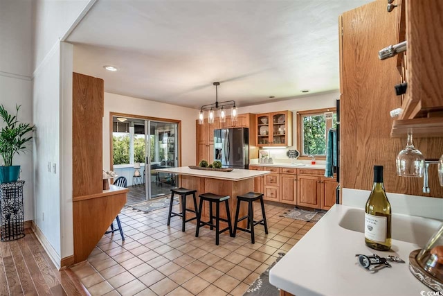 kitchen with stainless steel fridge, a breakfast bar area, a center island, light countertops, and healthy amount of natural light