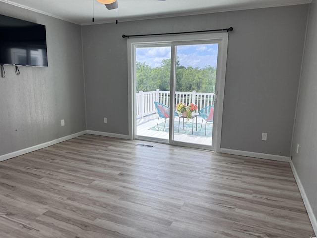 spare room with crown molding, ceiling fan, wood finished floors, and baseboards
