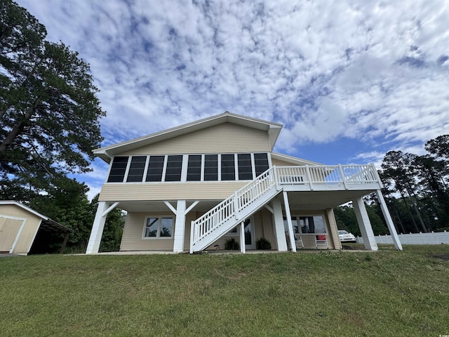 rear view of house with stairway, a storage unit, a deck, an outbuilding, and a yard