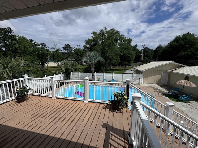 view of pool with a fenced backyard, a deck, a patio area, and view of wooded area