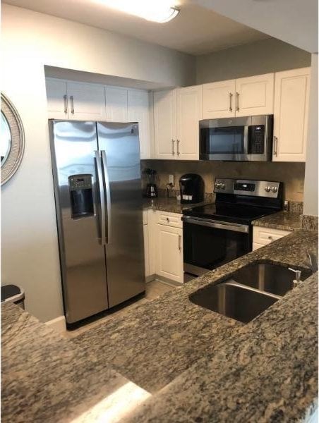 3000 Ocean Blvd N Unit 508, Myrtle Beach, SC 29577 - kitchen featuring appliances with stainless steel finishes, white cabinets, dark stone counters, and a sink