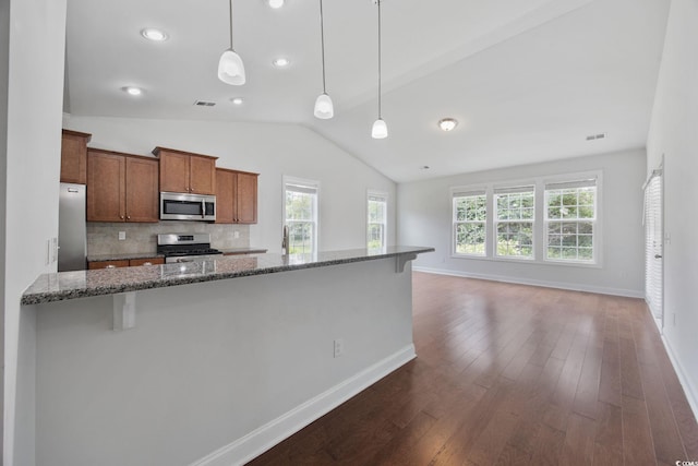 kitchen with appliances with stainless steel finishes, lofted ceiling, plenty of natural light, a kitchen bar, and decorative backsplash