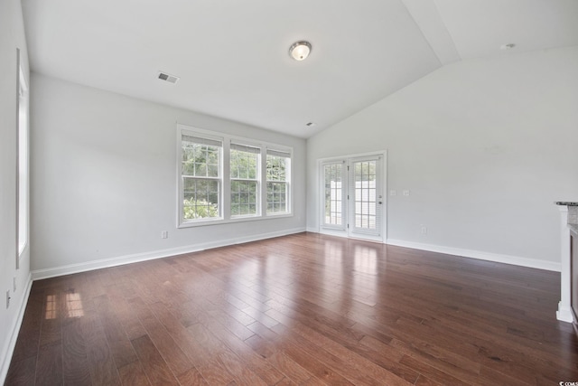 spare room featuring vaulted ceiling, dark wood-style flooring, and baseboards