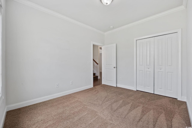 unfurnished bedroom with crown molding, carpet floors, baseboards, and a closet