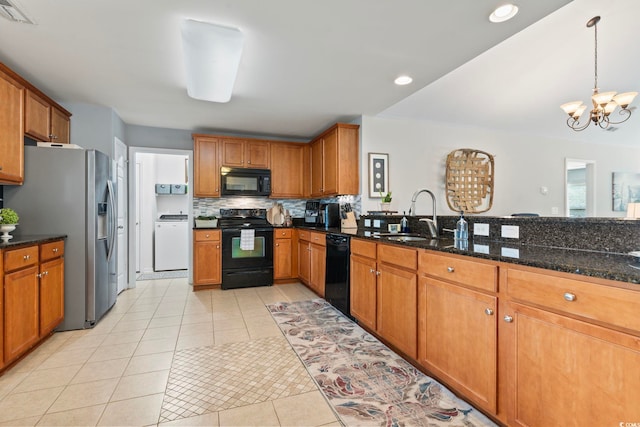 kitchen featuring black appliances, a sink, washer / clothes dryer, a chandelier, and brown cabinets