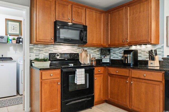 kitchen with black appliances, washer and clothes dryer, light tile patterned flooring, and dark stone countertops