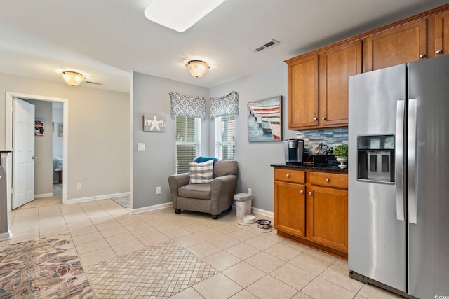kitchen with stainless steel refrigerator with ice dispenser, brown cabinetry, and light tile patterned flooring
