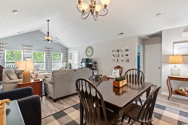 dining space featuring light wood-style flooring, vaulted ceiling, a ceiling fan, and a chandelier