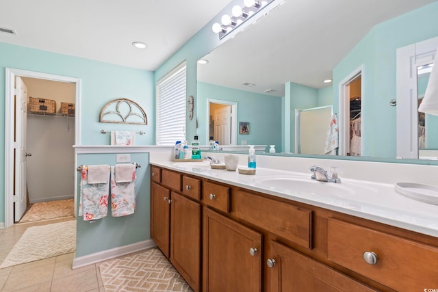 bathroom with tile patterned flooring, double vanity, a spacious closet, and a stall shower