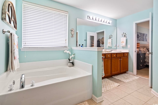 ensuite bathroom featuring a garden tub, vanity, and tile patterned flooring
