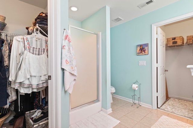 bathroom featuring a shower stall, toilet, tile patterned flooring, a walk in closet, and baseboards