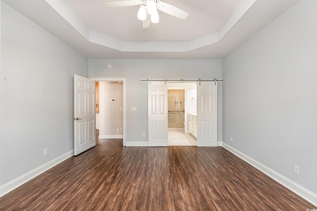 1435 Saint Thomas Cir Unit E-1, Myrtle Beach, SC 29577 - unfurnished bedroom featuring a tray ceiling, wood finished floors, a barn door, and baseboards