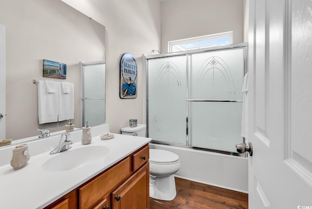 bathroom featuring wood finished floors, toilet, vanity, and enclosed tub / shower combo