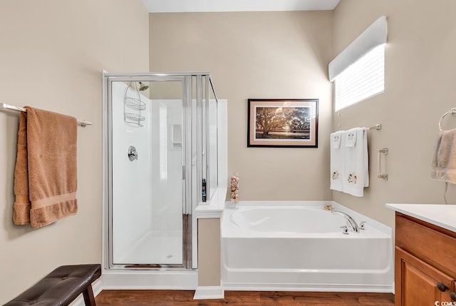 full bathroom with a shower stall, a bath, vanity, and wood finished floors