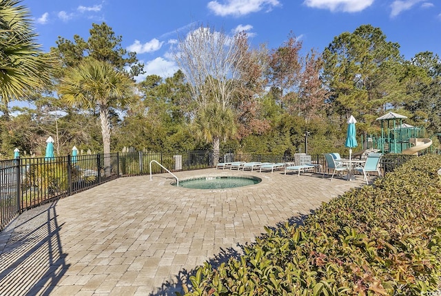 view of pool with fence, a hot tub, a patio area, and view of scattered trees
