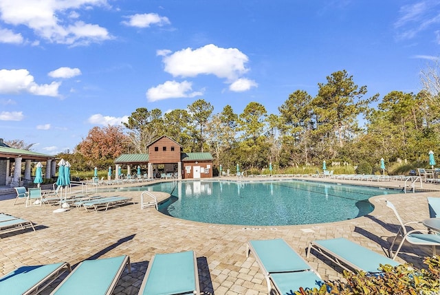 community pool with a patio area and view of scattered trees