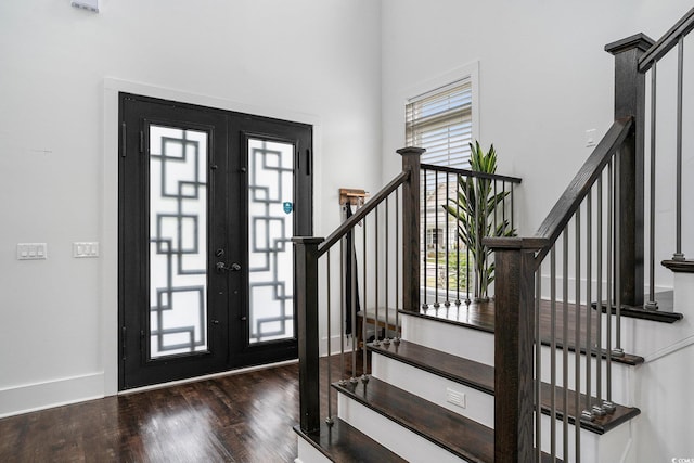 foyer entrance with plenty of natural light, stairway, wood finished floors, a high ceiling, and baseboards