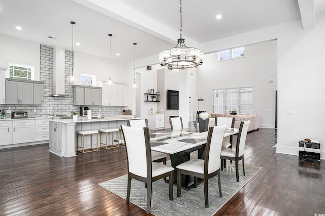 dining area with a chandelier, plenty of natural light, a towering ceiling, dark wood-type flooring, and recessed lighting