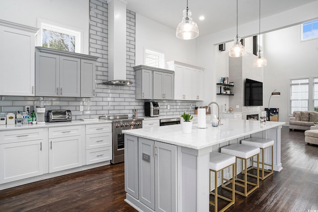 kitchen with stainless steel stove, a high ceiling, tasteful backsplash, a breakfast bar, and open floor plan