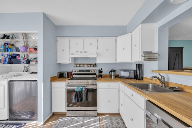 kitchen with appliances with stainless steel finishes, a sink, washing machine and clothes dryer, under cabinet range hood, and white cabinetry