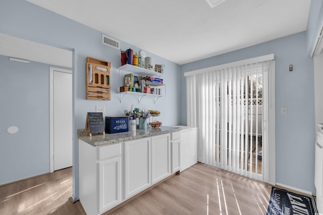 kitchen featuring light wood-type flooring, white cabinetry, light stone countertops, and open shelves
