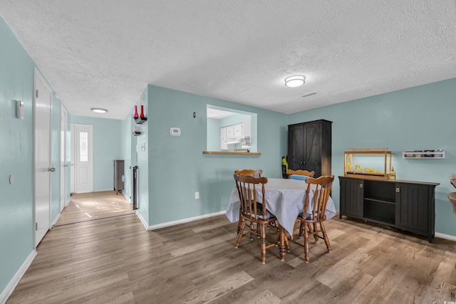 dining space with a textured ceiling, wood finished floors, and baseboards