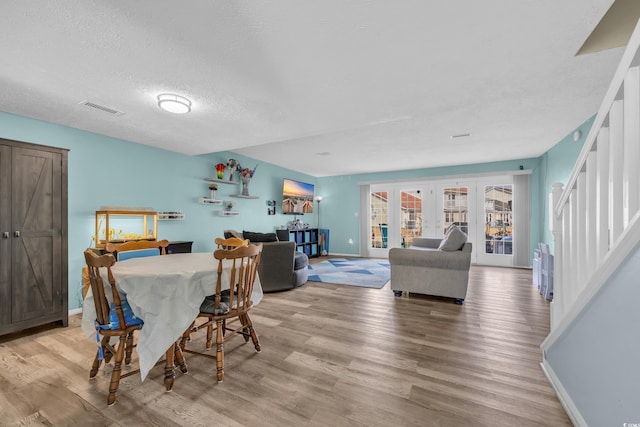 dining area featuring baseboards, light wood-style floors, stairs, and a textured ceiling