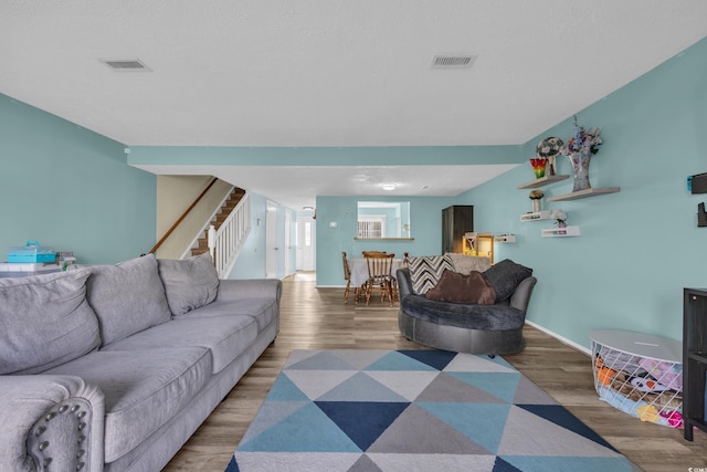 living room featuring wood finished floors, stairway, and baseboards
