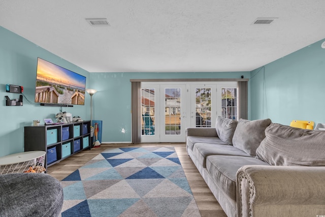 living room with french doors, wood finished floors, a textured ceiling, and baseboards