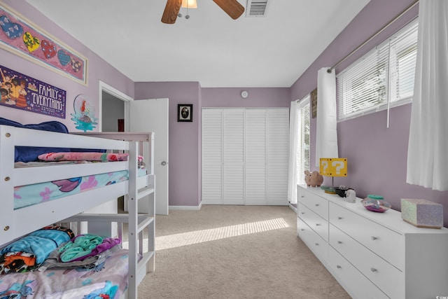bedroom with light colored carpet, a closet, and a ceiling fan