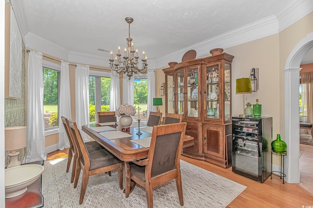 1206 Spinnaker Dr, North Myrtle Beach, SC 29582 - dining area featuring arched walkways, a chandelier, healthy amount of natural light, ornamental molding, and light wood finished floors