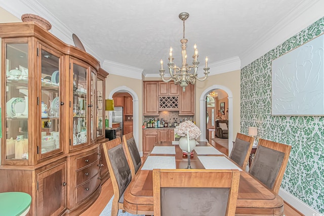 1206 Spinnaker Dr, North Myrtle Beach, SC 29582 - dining room with arched walkways, wallpapered walls, a chandelier, light wood-style flooring, and crown molding