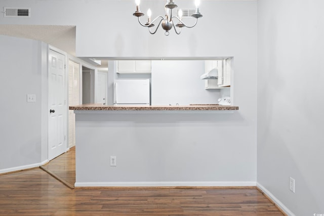 unfurnished dining area with wood finished floors, a chandelier, and baseboards