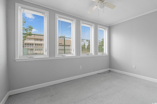 unfurnished room with speckle patterned floor, baseboards, a ceiling fan, and ornamental molding