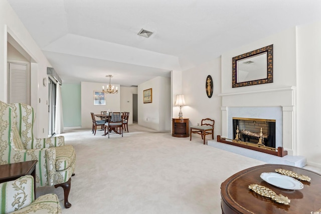 living room with a chandelier, carpet flooring, and a fireplace with raised hearth