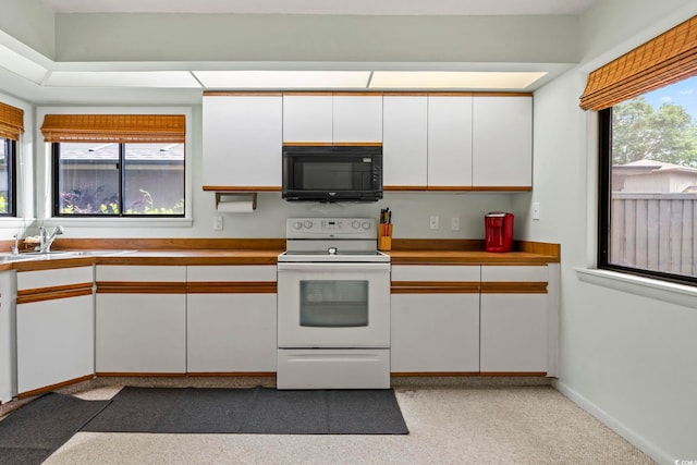 kitchen featuring white electric stove, black microwave, a sink, white cabinetry, and light countertops