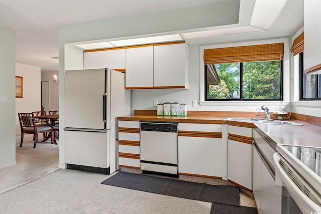 kitchen featuring white appliances, a sink, white cabinetry, and a chandelier