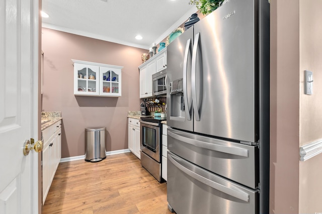 kitchen with stainless steel appliances, white cabinets, light wood-style flooring, glass insert cabinets, and light stone countertops