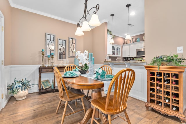 dining room with crown molding, wainscoting, light wood-type flooring, and recessed lighting