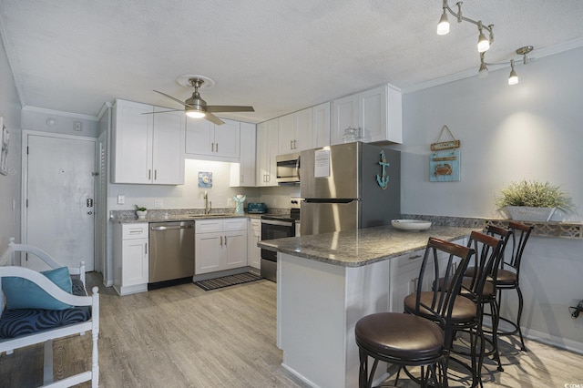 6000 N Ocean Blvd Unit 133, North Myrtle Beach, SC 29582 - kitchen with stainless steel appliances, ornamental molding, ceiling fan, white cabinetry, and a kitchen bar