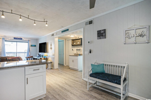 6000 N Ocean Blvd Unit 133, North Myrtle Beach, SC 29582 - kitchen featuring crown molding, light wood-style floors, white cabinetry, a textured ceiling, and a ceiling fan